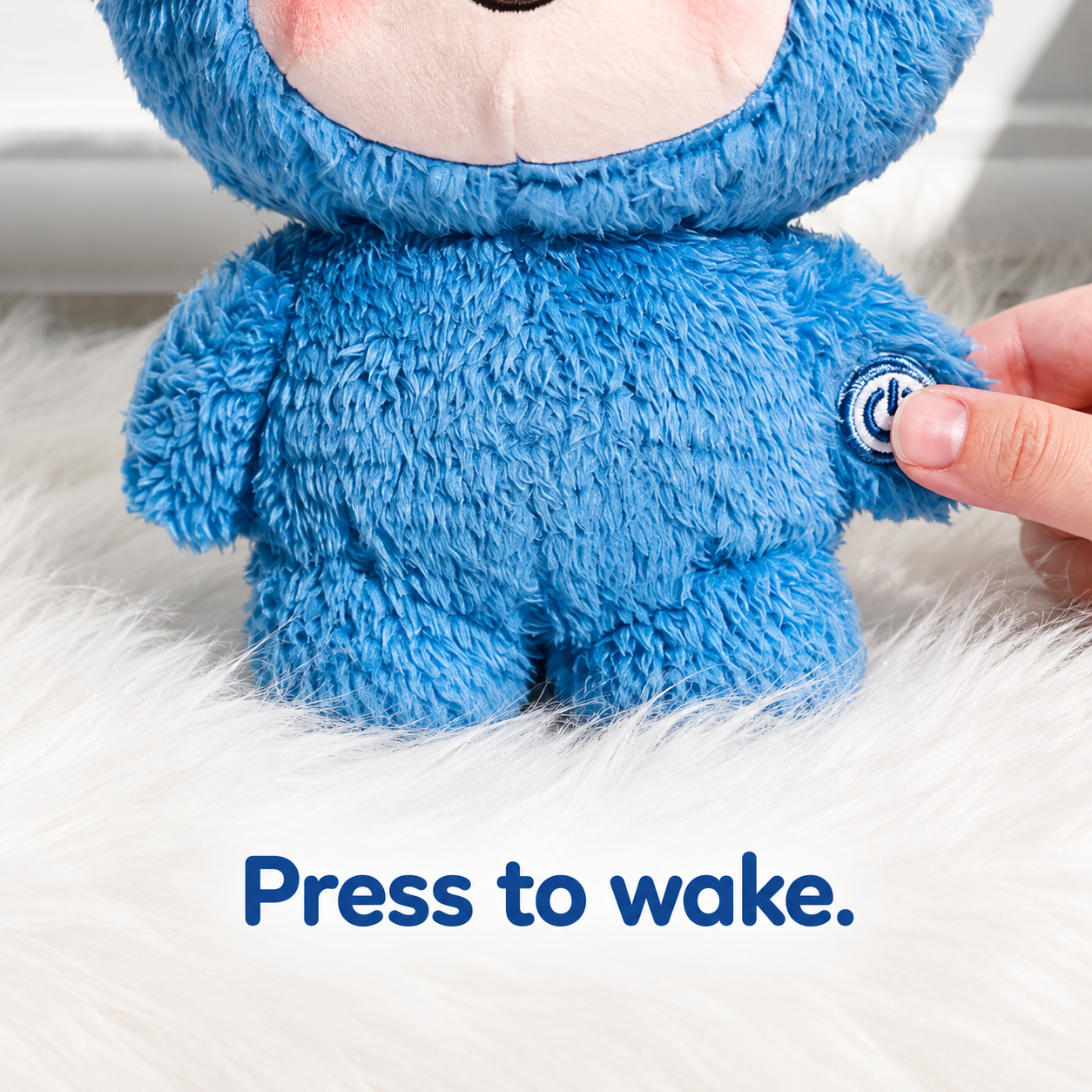 Close-up of the hand button on the blue AI Box plush companion: press to wake.